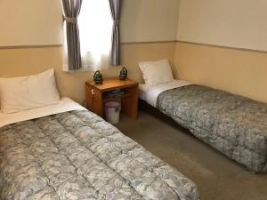 a room with two beds and a desk and a window at Petit Hotel Kurumi to Milk in Tateshina