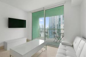 ein Wohnzimmer mit einem weißen Sofa und einem großen Fenster in der Unterkunft Centric Modern, Stylish Brickell / Miami + FREE Parking in Miami
