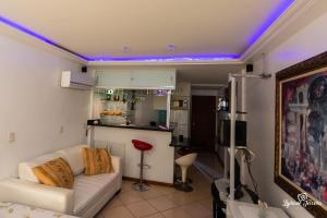 uma sala de estar com um sofá branco e uma cozinha em Loft da Prainha Resort AA 607 em Arraial do Cabo