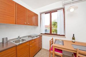 eine Küche mit einem Waschbecken, einem Tisch und einem Fenster in der Unterkunft Apartments Alluro in Rovinj