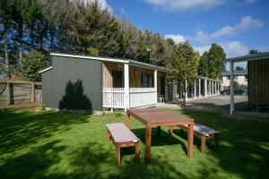 a picnic table and two benches in a yard at Mystery Creek Motel in Hamilton