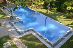 a swimming pool with blue water in a yard at Hostel Residence Bentota in Bentota