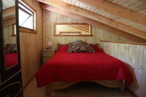 una camera con letto rosso in una cabina di Llaima Camp a Curacautín
