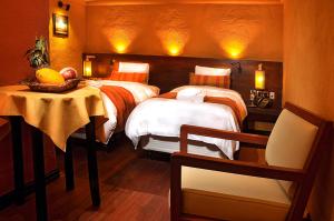 a bedroom with two beds and a table with a chair at Hotel Jardines de Uyuni in Uyuni