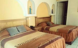 a bedroom with two beds and a cross on the wall at HOTEL BAEZA in Delicias