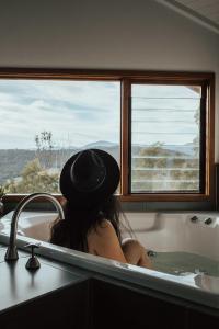 a woman sitting in a bath tub with a hat at Kangaroo Ridge Retreat in Healesville