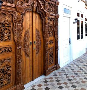 een grote houten deur met een tegelvloer bij The LaWang Yogya Guesthouse in Yogyakarta