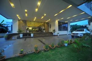 a car parked in front of a building with potted plants at Pipul Padmaja Premium Hotel in Bhubaneshwar