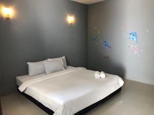 a bedroom with a bed with white sheets and butterflies on the wall at Pine Home in Krabi
