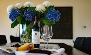 a bottle of wine and a glass and flowers on a table at The Roozen Residence in Prevelly