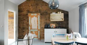 a kitchen with a wooden wall with a table and chairs at Nusfjord Arctic Resort in Nussfjord