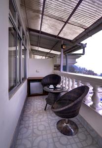 a patio with two chairs and a table on a balcony at Hotel White Yak in Darjeeling