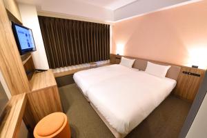 a bedroom with a white bed and a flat screen tv at Hakata Green Hotel Tenjin in Fukuoka