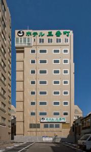 Un palazzo alto con un cartello sopra. di Hotel Sambancho a Matsuyama
