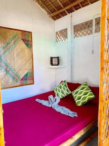 a bed in a room with two pillows at Suba Beach Nipa Huts in Daanbantayan