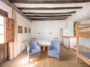 a bedroom with a bed and two blue chairs at Casa Rural Mas Garganta in La Pinya