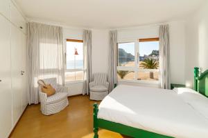 a bedroom with a bed and two chairs and windows at Edificio Tropicana in Tossa de Mar