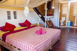 a bedroom with a bed with pink slippers on it at Kris Kos in Canggu