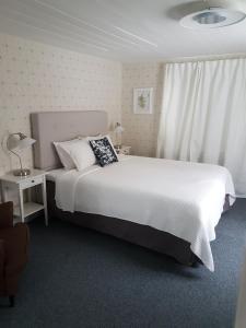 - une chambre avec un grand lit blanc et une fenêtre dans l'établissement Hedesunda Bed & Breakfast, à Hedesunda