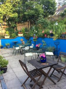 een patio met tafels en stoelen en een blauwe muur bij The Great Grubb in Totnes