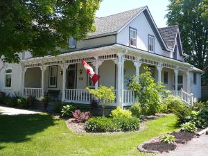 Gables Bed & Breakfast في Stayner: منزل أبيض مع علم في الفناء الأمامي