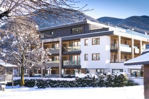 a white building with snow on the ground at Alpin Hotel Sonnblick in Perca