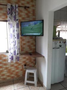 a television hanging on a brick wall with a stool at Casa Arthur Bernardes 15 in Arraial do Cabo