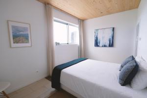 a bedroom with a white bed and two windows at Sao Vicente Lodge - Atlantic Retreat in São Vicente Ferreira