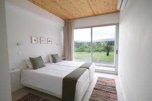 a bedroom with a bed and a large window at Sao Vicente Lodge - Atlantic Retreat in São Vicente Ferreira