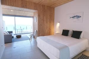 a bedroom with a white bed and a large window at Sao Vicente Lodge - Atlantic Retreat in São Vicente Ferreira