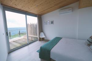 a bedroom with a bed and a view of the ocean at Sao Vicente Lodge - Atlantic Retreat in São Vicente Ferreira