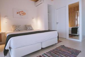 a white bedroom with a large white bed and a mirror at Sao Vicente Lodge - Atlantic Retreat in São Vicente Ferreira