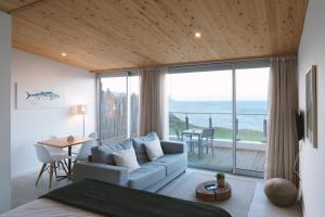 a living room with a couch and a view of the ocean at Sao Vicente Lodge - Atlantic Retreat in São Vicente Ferreira