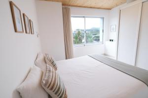 a white bedroom with a bed and a window at Sao Vicente Lodge - Atlantic Retreat in São Vicente Ferreira
