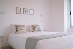 a white bed with two pillows on top of it at Sao Vicente Lodge - Atlantic Retreat in São Vicente Ferreira