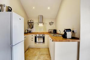 a kitchen with white cabinets and a white refrigerator at Llety Tyn y Coed in Creigiau