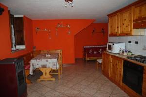 ラ・サルにあるCasa vacanza in centro a La Salleのオレンジの壁のキッチン(テーブル付)