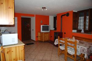 ラ・サルにあるCasa vacanza in centro a La Salleのオレンジ色の壁のキッチン、テーブル、テレビが備わります。