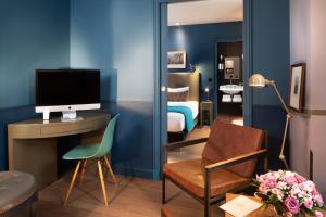 a living room with a couch, chair and a television at Hotel & Spa La Belle Juliette in Paris