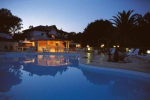 a swimming pool in front of a house at night at Camping Cavallo Morto in Bonifacio