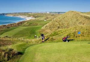 un grupo de personas en un campo de golf cerca del océano en Ballybunion Holiday Homes No 27, en Ballybunion