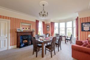 comedor con mesa, sillas y chimenea en Golf Lodge Bed & Breakfast, en North Berwick
