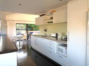 a kitchen with white cabinets and a dining room at Hahei Beach Apartment in Hahei