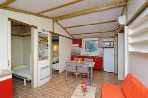 a kitchen and living room with red cabinets and a table at Camping Cavallo Morto in Bonifacio