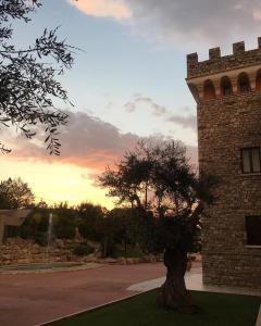 a tree in front of a building with a tower at Hotel Castello Torre in Pietra in Montefusco
