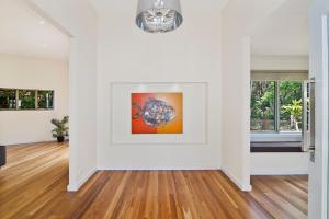 an empty living room with white walls and wood floors at Kilala - executive home in Port Macquarie