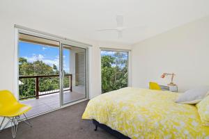 a bedroom with a bed and a balcony at Kilala - executive home in Port Macquarie