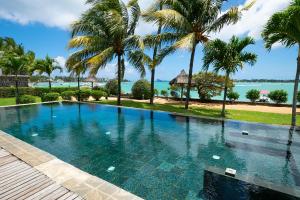 a swimming pool with palm trees and the ocean at Ocean Bay Villa in Grand-Baie