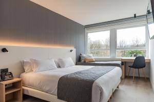 Un dormitorio con una cama y un escritorio y una ventana. en Hotel Distrito Oeste, en San Sebastián