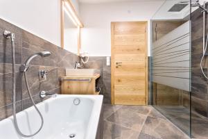 ein Bad mit einer Badewanne, einer Dusche und einem Waschbecken in der Unterkunft Tschörlerhof in Barbian